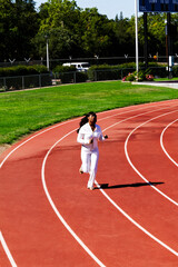 Fototapeta premium Young African American Woman Running On Track In White Sweat Suit