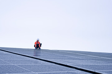 Engineer inspects wet solar panels on a rooftop under overcast sky