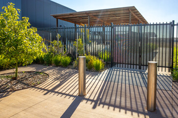 A gated pedestrian entrance or enclosure featuring vertical fencing and bollards to a school,...