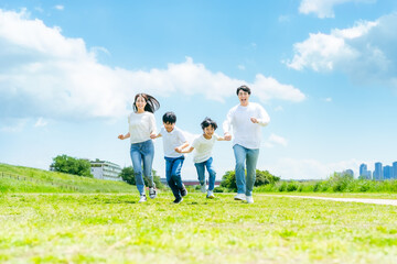 青空の草原を走る家族