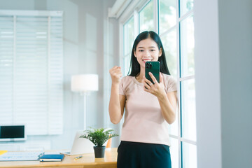Asian housewife relaxes at a table, using her smartphone for calls, chatting with friends, working...