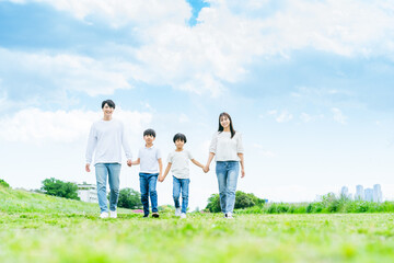 青空の草原を歩く家族