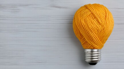 Creative concept: lightbulb made of yellow yarn on wooden background