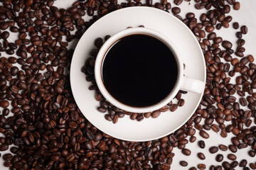 Freshly brewed black coffee in a white cup beside roasted beans on rustic table, capturing morning aroma, warmth, and cozy atmosphere.