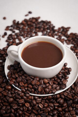Freshly brewed black coffee in a white cup beside roasted beans on rustic table, capturing morning aroma, warmth, and cozy atmosphere.