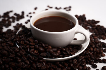 Freshly brewed black coffee in a white cup beside roasted beans on rustic table, capturing morning aroma, warmth, and cozy atmosphere.