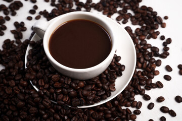 Freshly brewed black coffee in a white cup beside roasted beans on rustic table, capturing morning aroma, warmth, and cozy atmosphere.