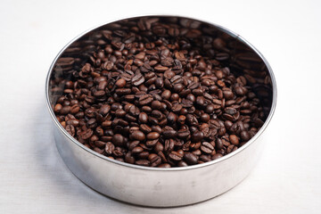 Close-up of roasted brown coffee beans piled together, showcasing rich texture, aroma, and freshness on a white studio background.