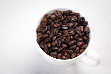 Close-up of roasted brown coffee beans piled together, showcasing rich texture, aroma, and freshness on a white studio background.