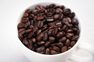Close-up of roasted brown coffee beans piled together, showcasing rich texture, aroma, and freshness on a white studio background.