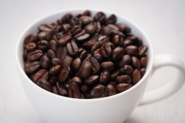 Close-up of roasted brown coffee beans piled together, showcasing rich texture, aroma, and freshness on a white studio background.