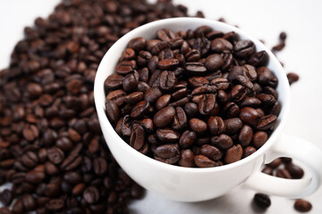 Close-up of roasted brown coffee beans piled together, showcasing rich texture, aroma, and freshness on a white studio background.