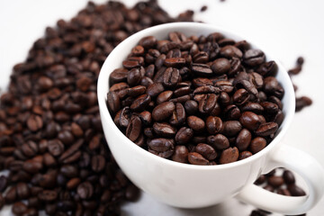 Close-up of roasted brown coffee beans piled together, showcasing rich texture, aroma, and freshness on a white studio background.