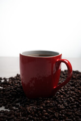 Freshly brewed black coffee in a white cup beside roasted beans on rustic table, capturing morning aroma, warmth, and cozy atmosphere.