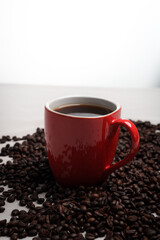 Freshly brewed black coffee in a white cup beside roasted beans on rustic table, capturing morning aroma, warmth, and cozy atmosphere.