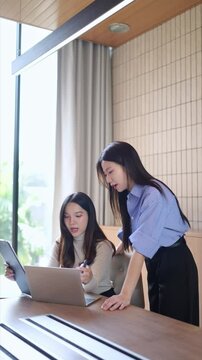 Coaching style adult asian businesswomen teamwork as leader provides feedback on laptop work to her team members an an asian businesswomen teamwork focused on improving work quality.