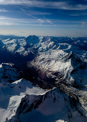 An aerial shot of the Swiss Alps mountain range on a sunny day with blue skies