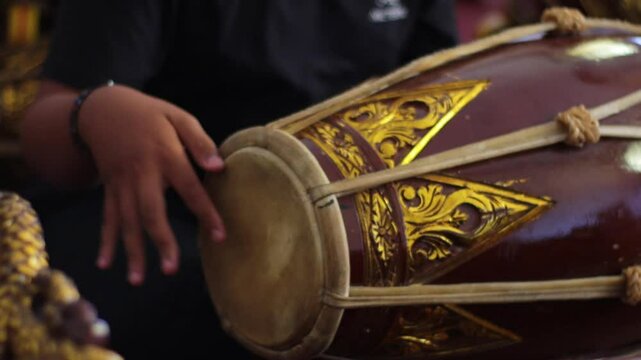 close up of a gamelan player hitting Kendang
