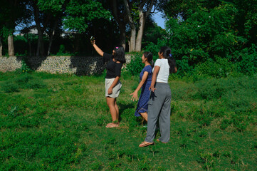 Fototapeta premium The girls joyfully pose and smile as they take a selfie together in a field surrounded by wild greenery.
