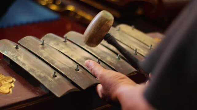 close up of a gamelan player striking Saron