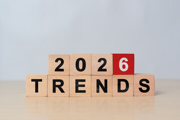 Hand flipping wooden block cube to change from 2025 to 2026 trends for business , fashion and technology trend change concept after new year