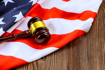 Justice wooden gavel rests on draped American flag, symbolizing justice, legal proceedings in US courtroom