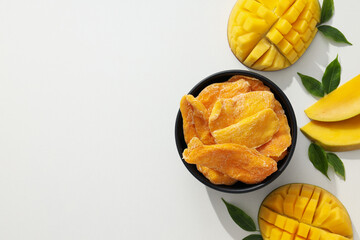 A bowl of dried mango chips with fresh sliced mango