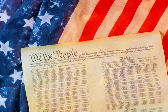U.S. Constitution on an American flag symbolizes nation history, democracy, freedom.