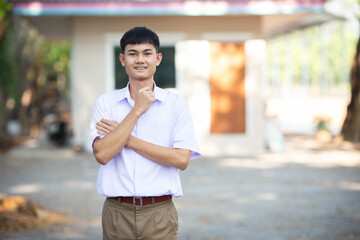 Fototapeta premium Thai boy student in official Thai school uniform (khaki or brown shorts), properly dressed, stand firmly with arms crossed, horizontal image