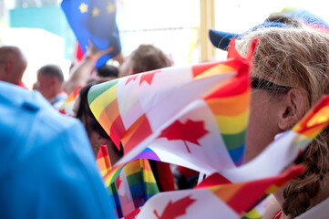 Close up, People in the parade carry the Rainbow Canadian Pride flags to celebrate the Pride Month.