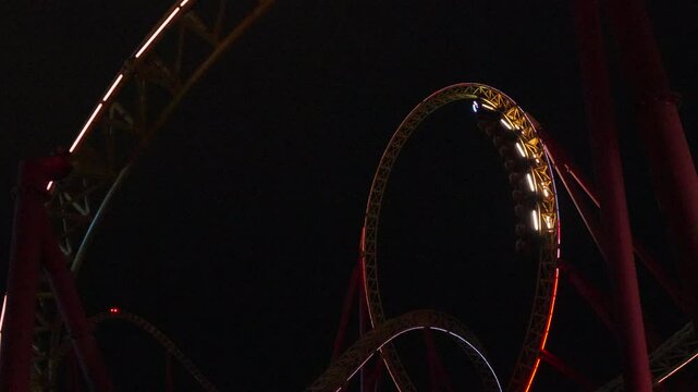 Rollercoaster Night Ride Amusement Park: Illuminated Looping Track at Night.