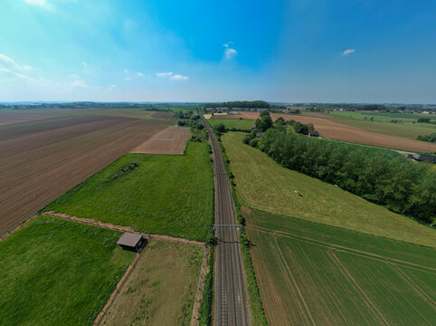 Breathtaking aerial view of serene countryside landscape featuring roads, green fields, and blue skies.