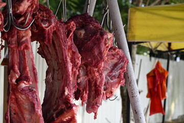 A close-up view of freshly slaughtered cow carcasses hanging on metal hooks during the week of Eid al-Adha, also known as Hari Raya Haji, a significant Islamic festival in Malaysia.