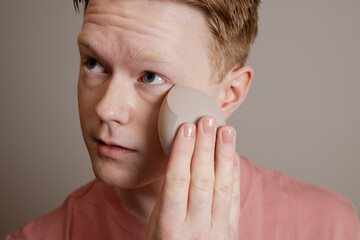 A Close-up Of A Young Man Applying Foundation Skincare Makeup Routine
A young man applies...