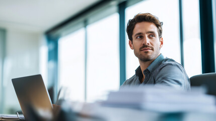 Obraz premium Confident young businessman working at his desk in a modern office environment. 