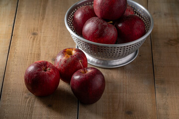 Some vibrant red apples rest on a rustic wooden background, highlighting their fresh appeal. Perfect for themes related to healthy eating, natural food, or autumn harvest.