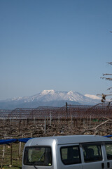 Vertical image of the Japanese landscape of the Japanese Alphes a stunning mountain range with snow outdoor at daytime in spring on the countryside between the vines of Nagano in Japan.
