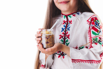 Beautiful bulgarian girl wearing traditional folklore costume eating bulgarian sweet meal ashura made from wheat, rose water, nuts and dried fruits