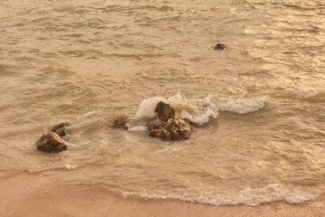 Waves crashing over rocky beach during sunset at coastal shore