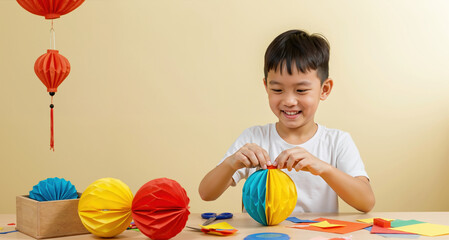 Asian boy making colorful paper lanterns with scissors on table next to hanging red decorations. Chinese new year craft activities for cultural celebrations and festivals