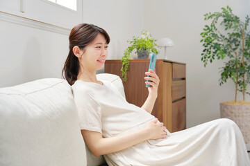 スマートフォンを使う妊婦　リビング