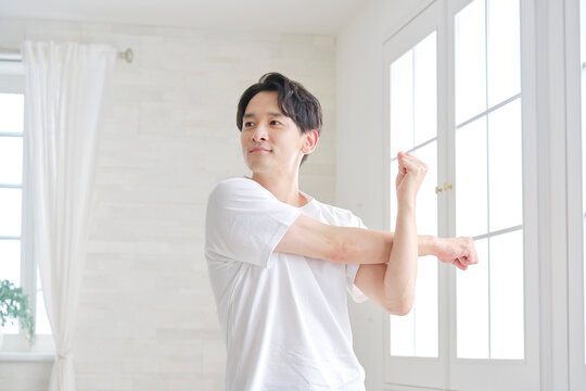 自宅で腕のストレッチする男性