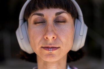 Young woman listening to music on headphones. Stylish girl listening to songs through wireless...