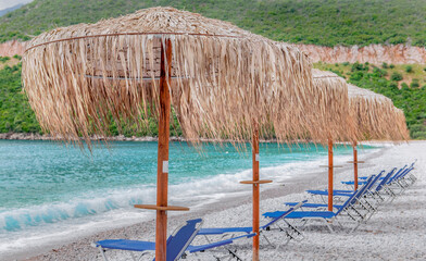 straw umbrella and sun loungers on a white pebble beach in Peloponnese Greece