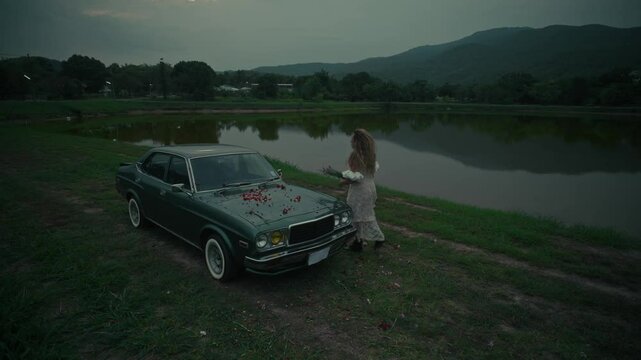 A touching emotional scene unfolds by an old car situated near the waters edge