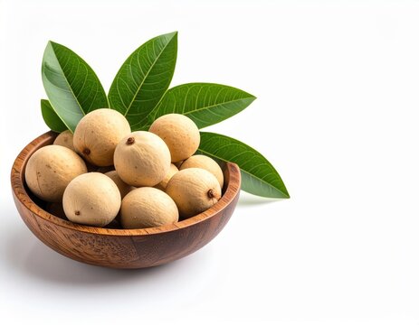 A wooden bowl brimming with fresh, ripe lanzones fruit rests on a pristine white background, adorned with vibrant green leaves adding a touch of natural elegance.