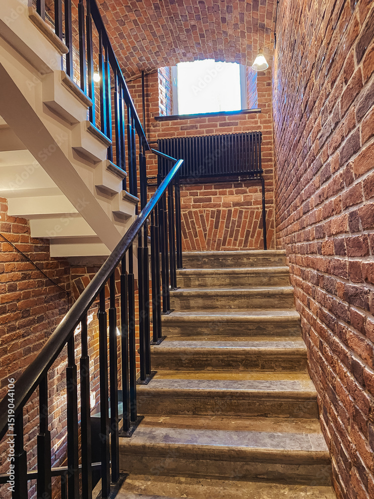 Poster staircase in an old brick building with natural light illuminating the steps and walls