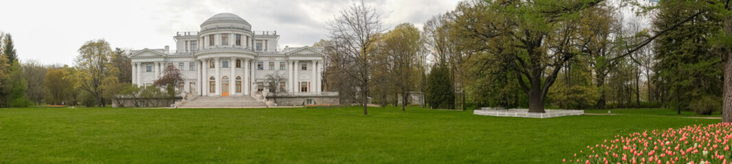 Elegant Historic Mansion Surrounded by Vibrant Gardens and Lush Greenery in Early Spring
