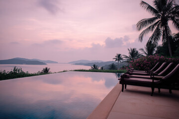 A sleek rooftop infinity pool reflects a serene sunset over the ocean, surrounded by palm trees and lush greenery creating a tranquil and luxurious atmosphere