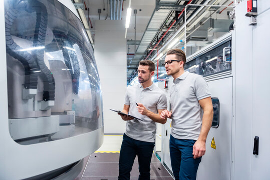 Two employees discussing in a production hall with machinery